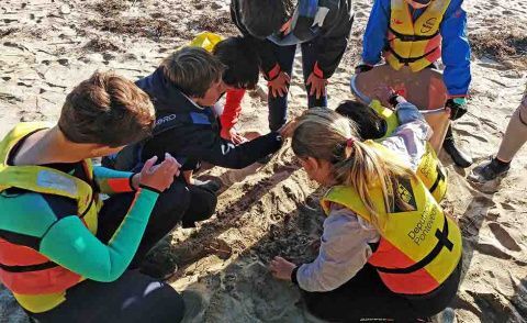 Niños de la Escuela de Vela del Monte Real Club de Yates recogiendo plásticos en la playa. /© David Fontán